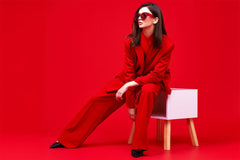Fashion model in red suit and sunglasses. Studio shot.