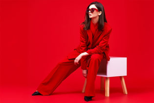 Fashion model in red suit and sunglasses. Studio shot.